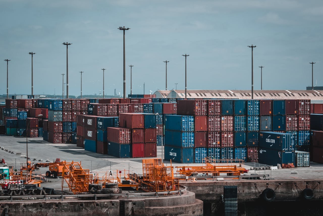 why-choose-us Colorful cargo containers stacked at a busy industrial port, showcasing global trade.